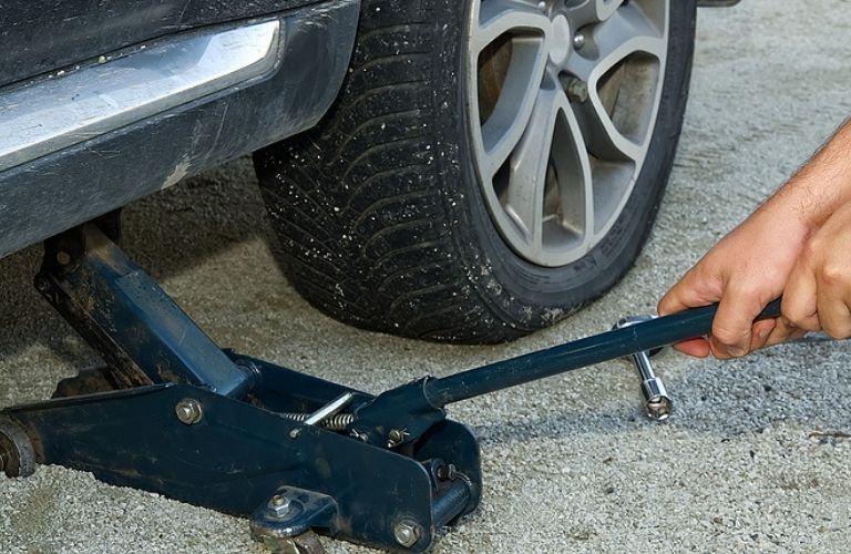 Image of a person using a jack to raise the vehicle