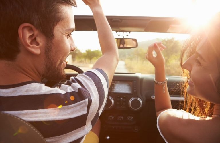 a couple looking at each other and laughing while driving