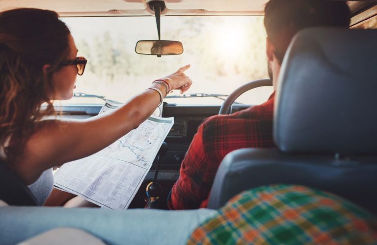 A couple travelling in a car while looking at a map.