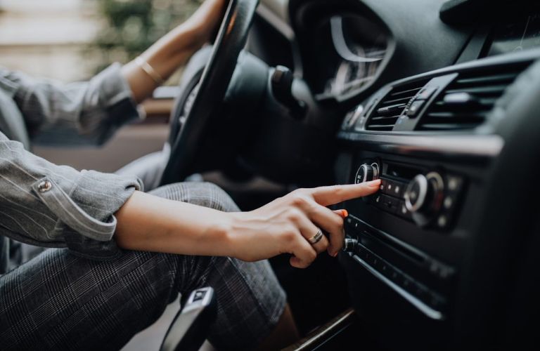 Close up of a hand adjusting the music feature of a car.