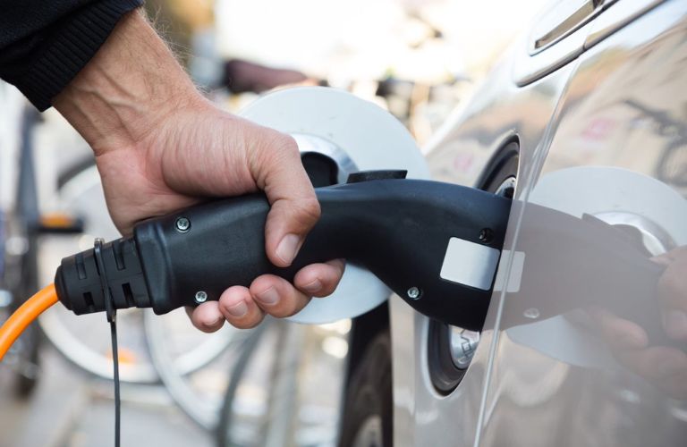 Close up image of a hand charging an electric vehicle.