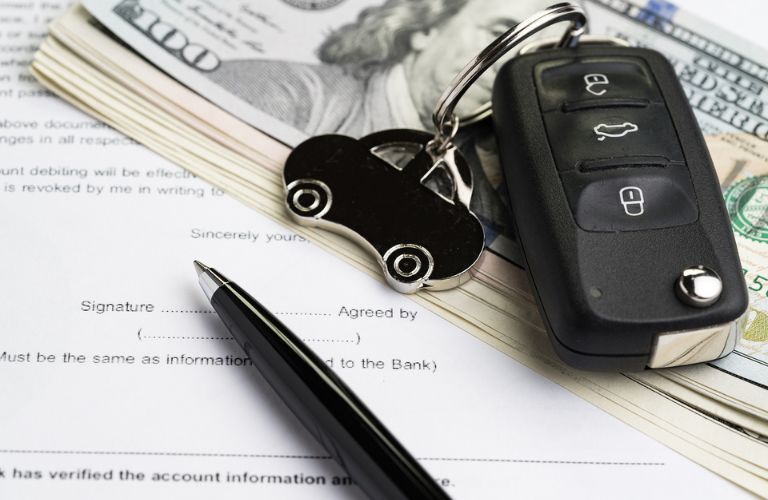 Car keychain on pile of US dollars