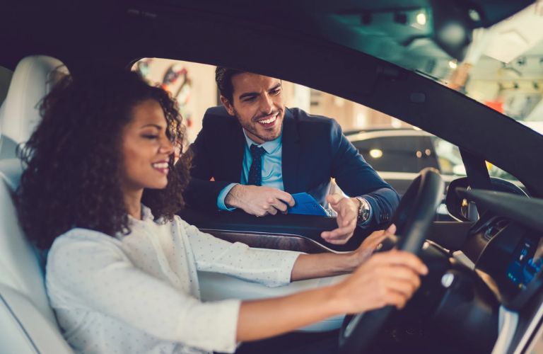 A woman assisted by a salesman before driving a car