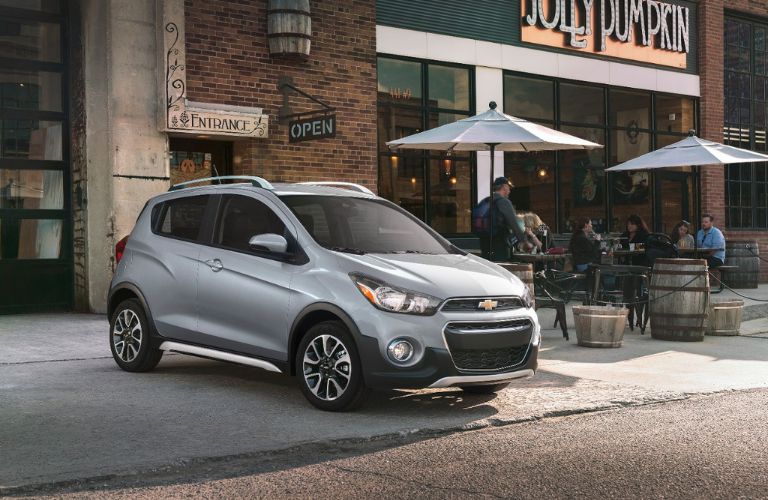 A grey 2021 Chevrolet Spark parked outside a restaurant. 