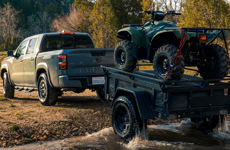 Rear view of the 2023 Nissan Frontier PRO-4X towing a quad-bike