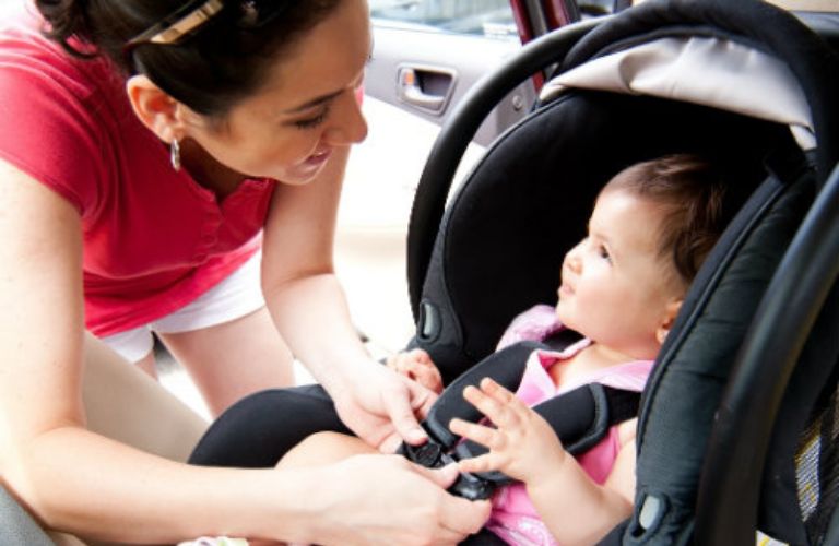 Woman talking to a toddler sitting in a car seat