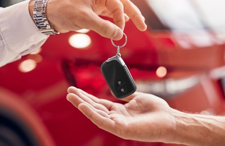 A person is handing over a car key to another person