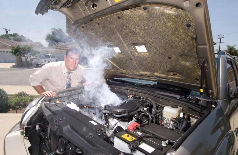 A man looking at an overheated can engine 