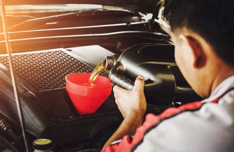Mechanic pouring oil from a can into a funnel